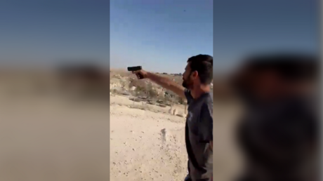 A screenshot from a video shows Yinon Levi brandishing a gun.