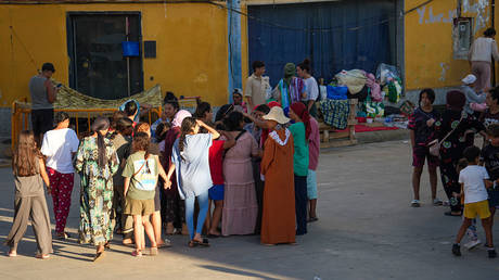 Women migrants and children gather in an industrial area in Ceuta, Spain, after crossing from Morocco, August 3, 2026.