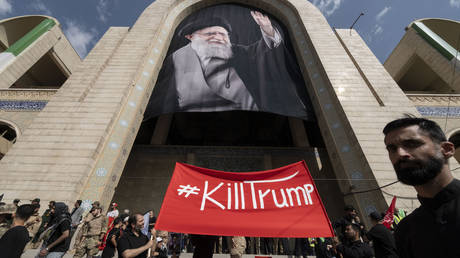 Iranian mourners hold an anti-Trump banner beneath a portrait of Ali Khamenei in Tehran on July 4, 2026.