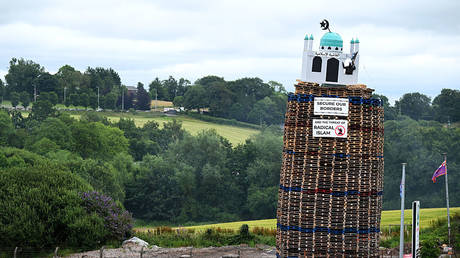 A model depicting a mosque sits atop a stack of pallets ahead of a bonfire in Moygashel, Northern Ireland, July 9, 2026
