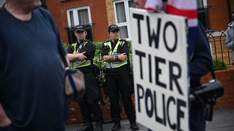 A protester holds a sign stating 'two tier police' during a demonstration about the death of Henry Nowak in Southampton, England, June 7, 2026