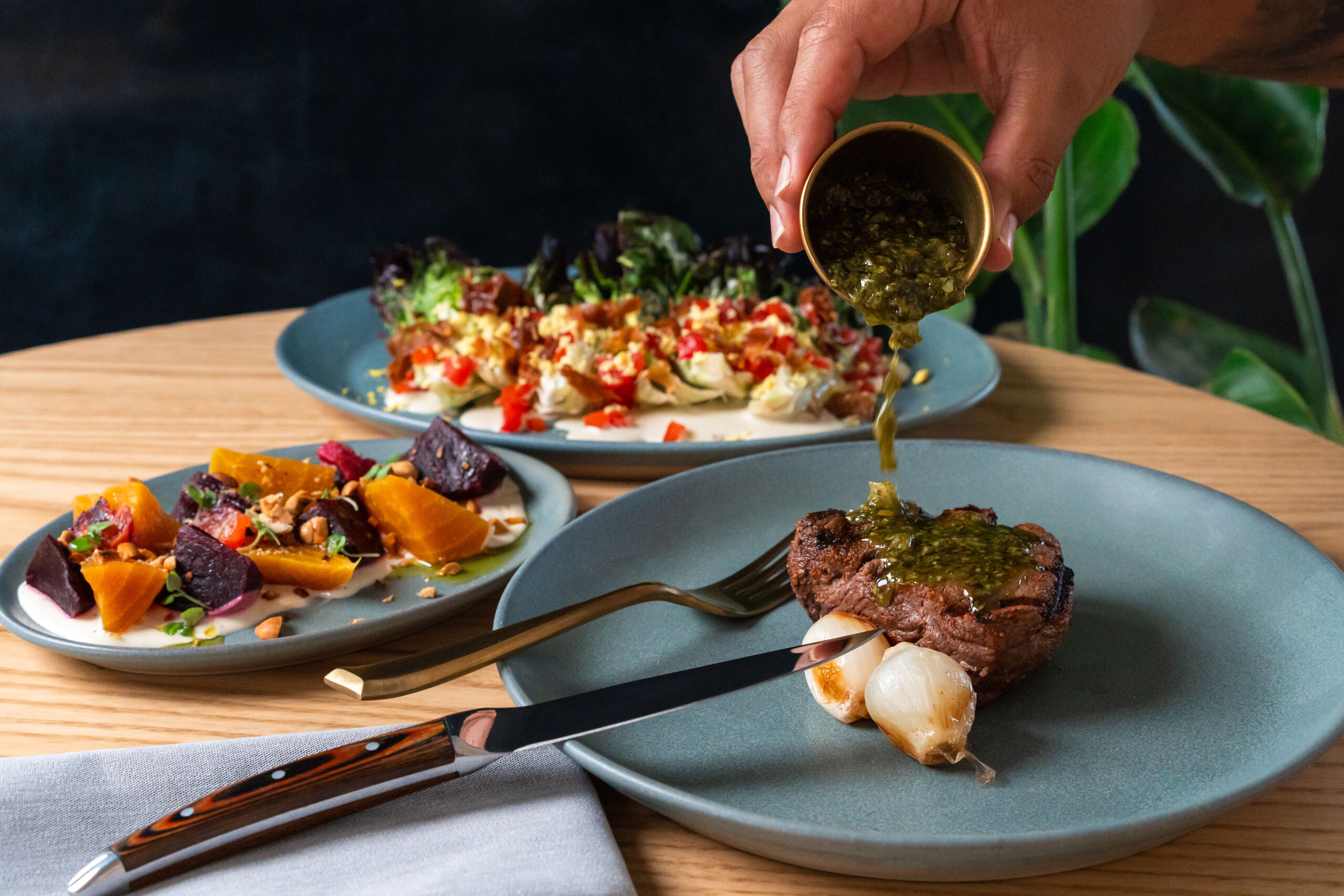 hand drizzling sauce over plated dishes sitting on table