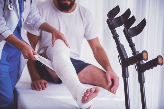 Injured man receiving medical treatment for a bandaged leg after an accident