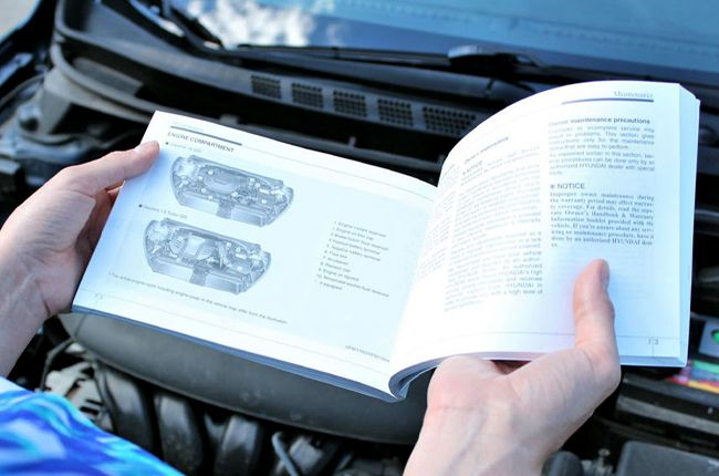 Driver reviewing a car manual to make an informed maintenance decision