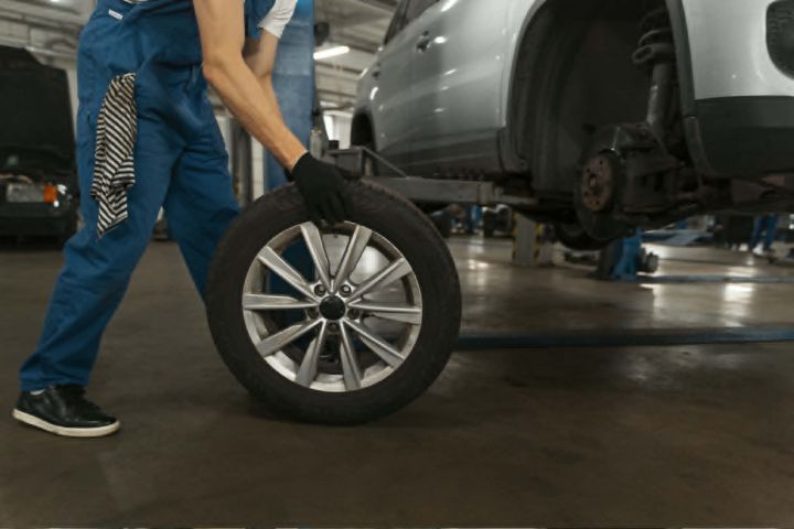 Technician using a wheel balancer for a large alloy wheel and low-profile tire