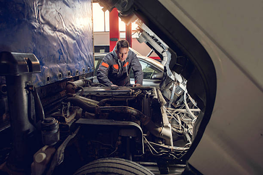 Mechanic inspecting a semi-truck before selecting aftermarket parts for Kenworth trucks