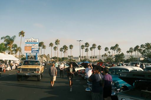 People walking past classic cars at a sunny outdoor event