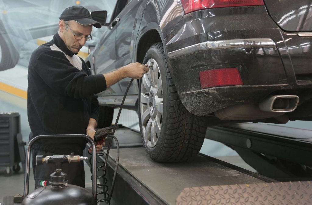 Technician inflating an SUV tire in a service shop