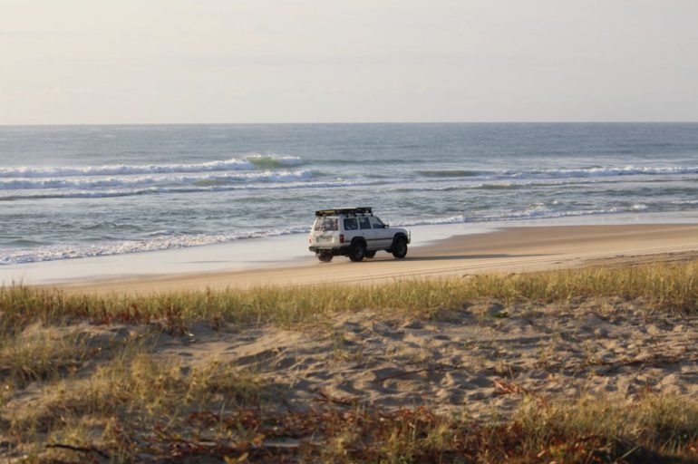 A modern SUV parked near an Australian beach at sunset